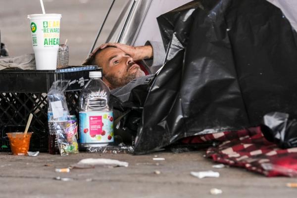 A homeless man lays on the ground as officials clear out the area ahead of Taylor Swift's concerts.