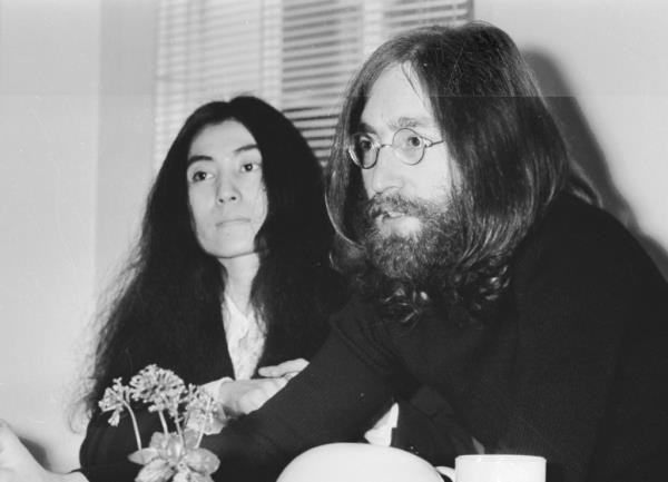 John Lennon and Yoko Ono sitting at a table during an interview in 1969, advocating for peace