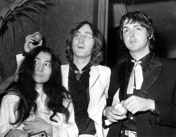 18th July 1968: Beatle John Lennon (1940 - 1980) and his Japanese girlfriend Yoko Ono with Beatle Paul McCartney, right, at the premiere of the new Beatles film 'Yellow Submarine' at the Lo<em></em>ndon Pavilion. John and Paul hold apples, the symbol of their newly formed company, Apple Corps. Thousands of Beatle fans brought traffic to a standstill in Piccadilly Circus as they waited to see the group arrive at the premiere. (Photo by Michael Webb/Keystone/Getty Images)